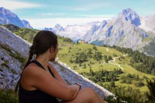 Frau sitzt am Berg und genießt Aussicht