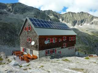 Eine holzverschandelte Hütte mit roten Fensterläden im Hochgebirge.