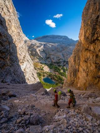 Zwei Menschen laufen steilen Pfad zwischen zwei Felswänden hinab