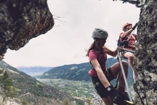 Zwei Menschen auf Klettersteig in luftiger Höhe