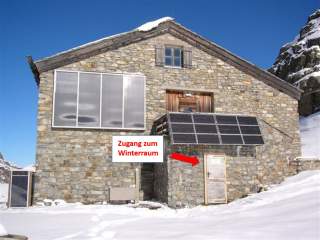 Steinhütte mit Solarpanels im Winter