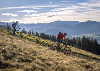 Zwei Menschen auf Mountainbikes fahren Berghang runter