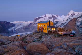 Hütte im Abendlicht vor Bergen und Gletschern