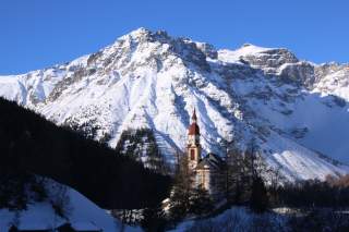 Barockkirche vor mächtigen, schneebedeckten Gipfeln
