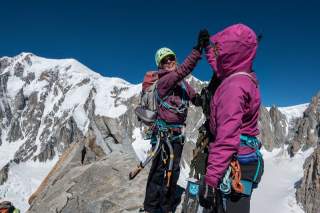 Zwei Frauen klatschen auf Gipfel ab