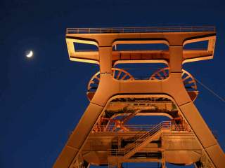Blaue Stunde in der Zeche Zollverein, neben der rot-rostigem Stahlarchitektur der abnehmende Mond.